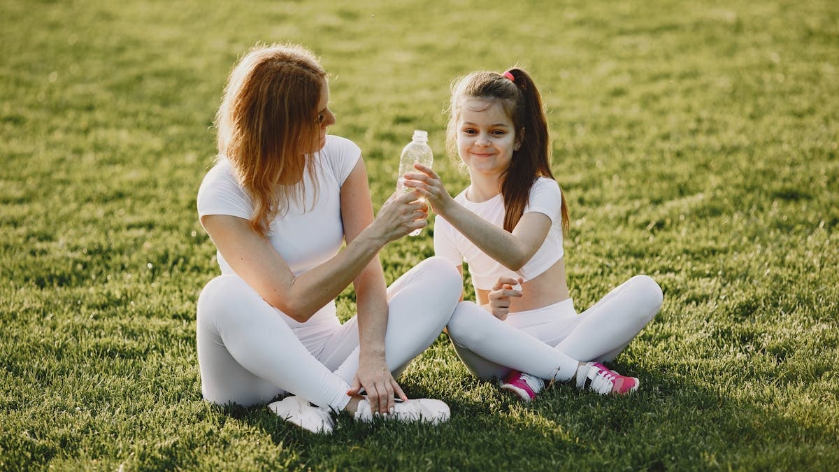Caucasian mother and daughter in sportswear sharing a bonding moment outdoors.